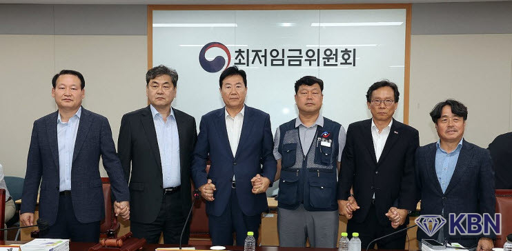 이인재 최저임금위원장(왼쪽 두 번째)이 10일 정부세종청사에서 열린 제12차 전원회의에서 내년 최저임금을 시간당 1만320원으로 17년만에 합의로 결정한 뒤 공익위원-사용자위원-근로자위원과 손을 잡고 있다.